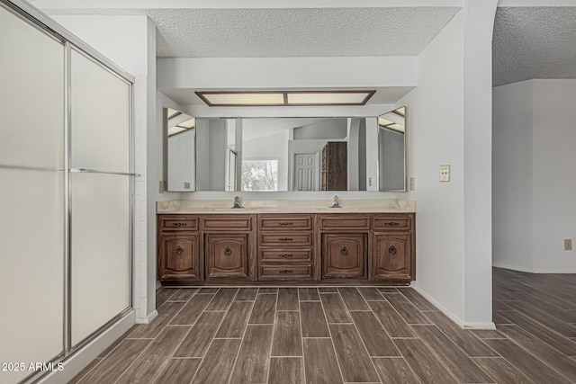6701 W Monterey Way, Phoenix, AZ 85033 - full bath featuring wood finished floors, a textured ceiling, a shower stall, double vanity, and baseboards