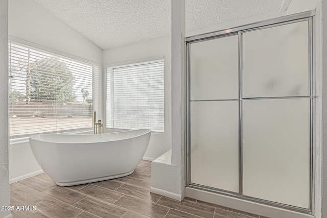 6701 W Monterey Way, Phoenix, AZ 85033 - bathroom featuring a textured ceiling, a stall shower, wood tiled floors, a freestanding bath, and baseboards