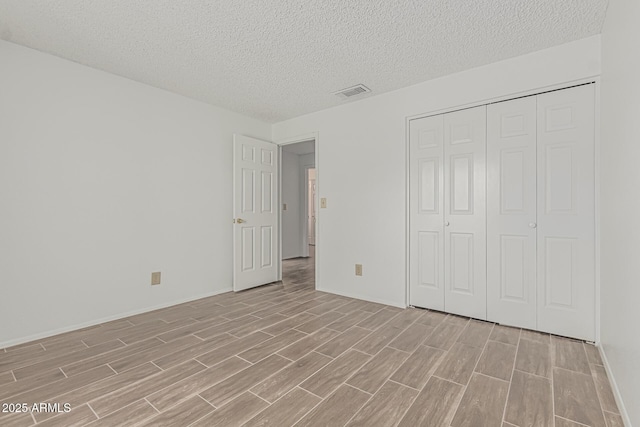 6701 W Monterey Way, Phoenix, AZ 85033 - unfurnished bedroom featuring light wood-style floors, a textured ceiling, a closet, and baseboards