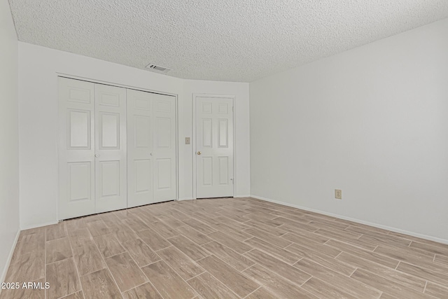 6701 W Monterey Way, Phoenix, AZ 85033 - unfurnished bedroom featuring light wood-type flooring, a textured ceiling, a closet, and baseboards