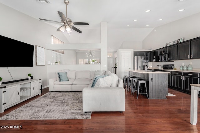 living area with recessed lighting, ceiling fan with notable chandelier, high vaulted ceiling, and dark wood-type flooring