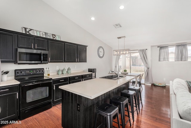 kitchen featuring stainless steel microwave, black electric range oven, dark cabinetry, and visible vents