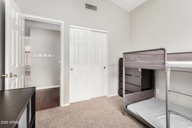 carpeted bedroom with visible vents, a closet, and baseboards