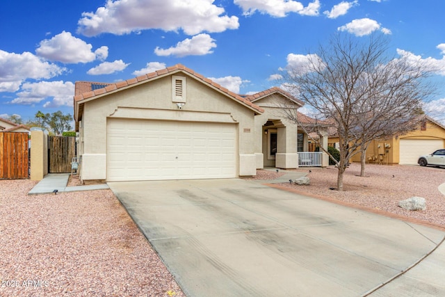 ranch-style home featuring stucco siding, an attached garage, driveway, and a gate