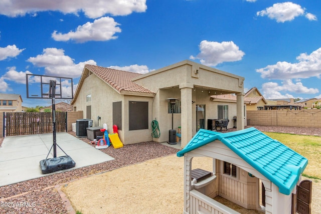 rear view of house featuring a gate, cooling unit, a fenced backyard, stucco siding, and a tiled roof