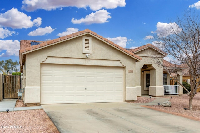 view of front of property featuring fence, a tile roof, stucco siding, a garage, and driveway