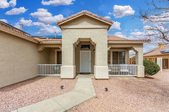 exterior space featuring stucco siding, covered porch, solar panels, and a tiled roof