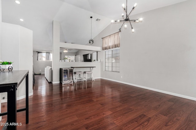 living area with baseboards, lofted ceiling, wood finished floors, and ceiling fan with notable chandelier