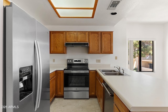 19400 N Westbrook Pkwy Unit 220, Peoria, AZ 85382 - kitchen featuring appliances with stainless steel finishes, a peninsula, range hood, and brown cabinets