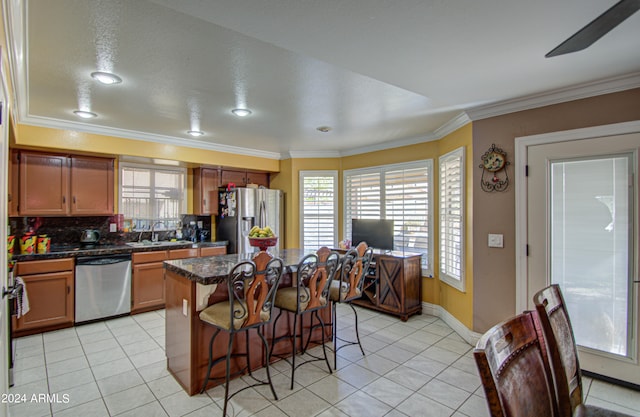 kitchen featuring decorative backsplash, a kitchen bar, stainless steel appliances, sink, and a center island