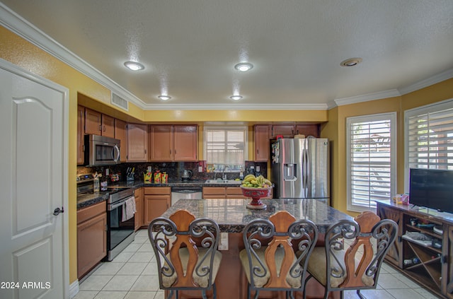 kitchen featuring crown molding, stainless steel appliances, a center island, and light tile patterned flooring