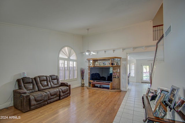 living room with crown molding, light wood-type flooring, and ceiling fan