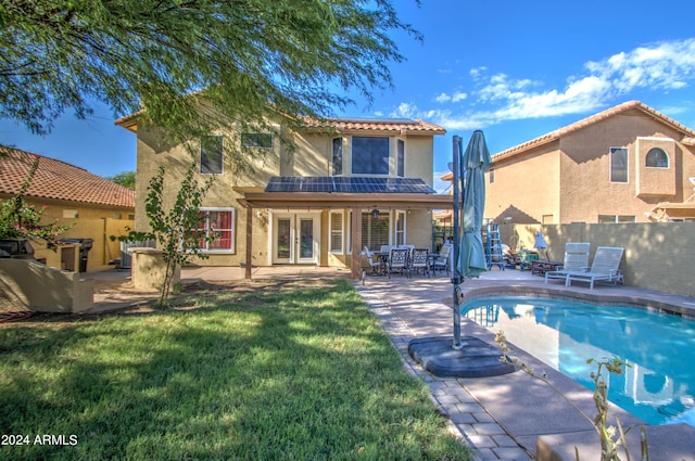 rear view of house featuring a patio, a fenced in pool, french doors, and a yard