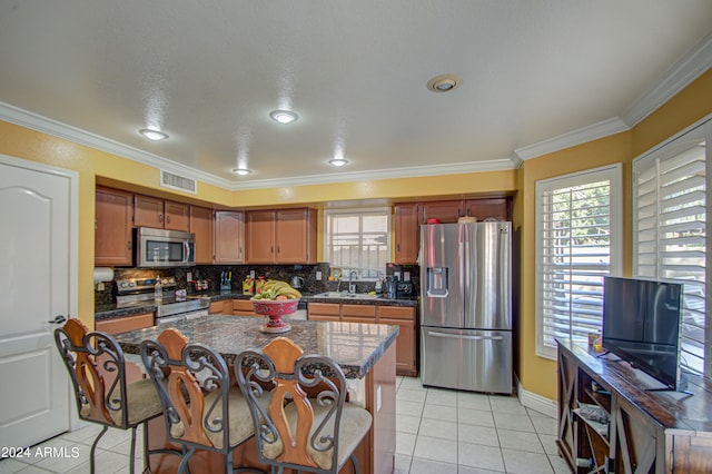 kitchen featuring a center island, ornamental molding, a healthy amount of sunlight, and stainless steel appliances