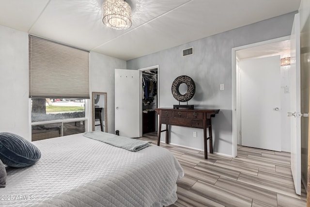 bedroom with a walk in closet and a chandelier