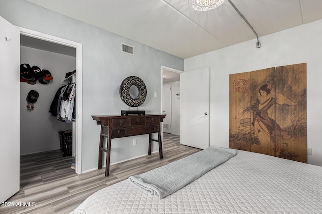 bedroom with wood-type flooring, a spacious closet, and a closet