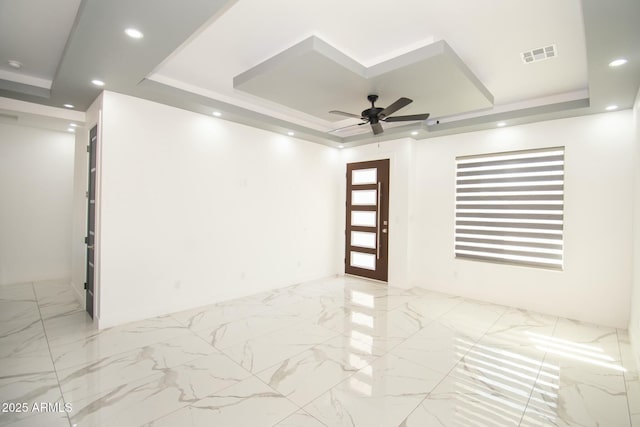 spare room with a tray ceiling and ceiling fan