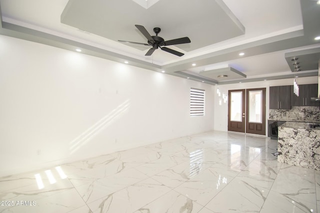 unfurnished room with a raised ceiling, ceiling fan, and french doors