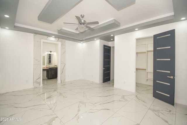 interior space featuring ensuite bathroom, a raised ceiling, ceiling fan, a spacious closet, and a closet