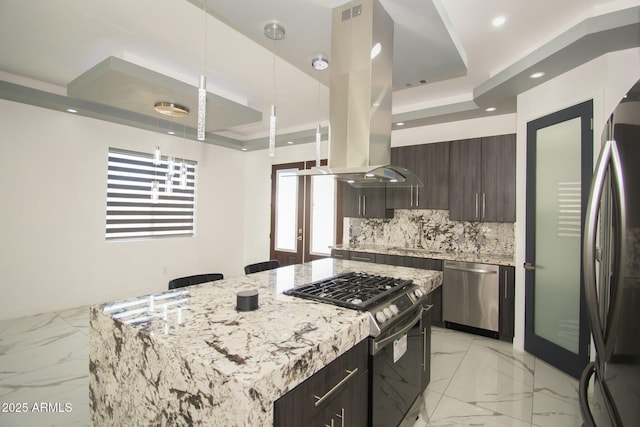 kitchen featuring island exhaust hood, a center island, stainless steel appliances, and a tray ceiling