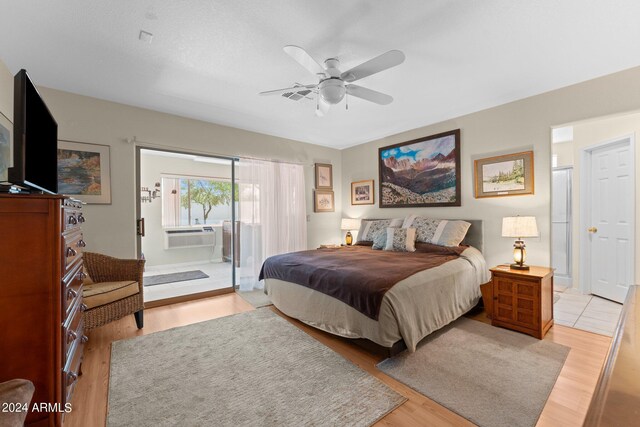 bedroom with cooling unit, ceiling fan, light wood-type flooring, and ensuite bathroom