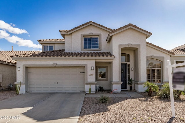 mediterranean / spanish house featuring a tiled roof, stucco siding, an attached garage, and concrete driveway