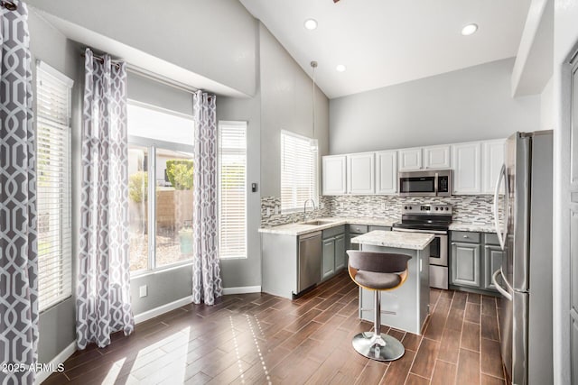 kitchen with tasteful backsplash, appliances with stainless steel finishes, a center island, and wood tiled floor