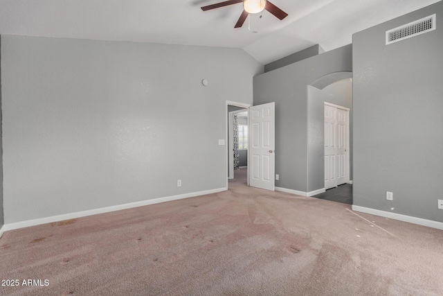 unfurnished bedroom with carpet, visible vents, baseboards, arched walkways, and vaulted ceiling