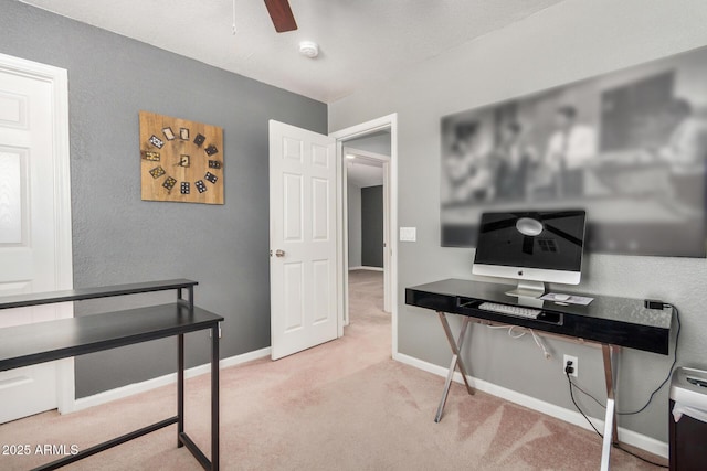 carpeted office space featuring ceiling fan and baseboards