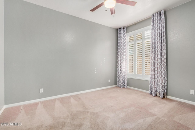 carpeted spare room featuring baseboards and ceiling fan