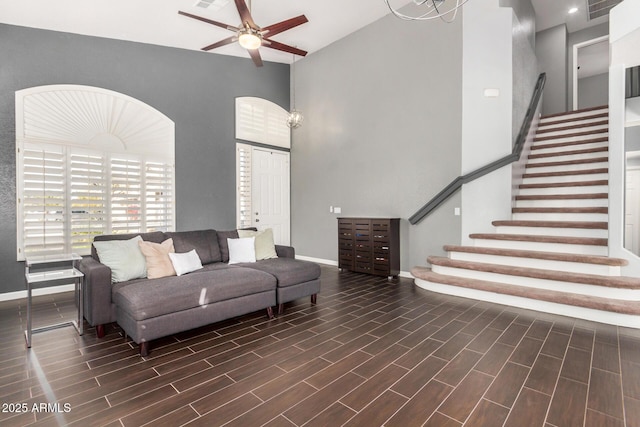 living room featuring stairway, baseboards, a towering ceiling, and wood finish floors