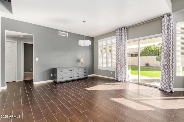 spare room with wood finish floors, visible vents, and baseboards