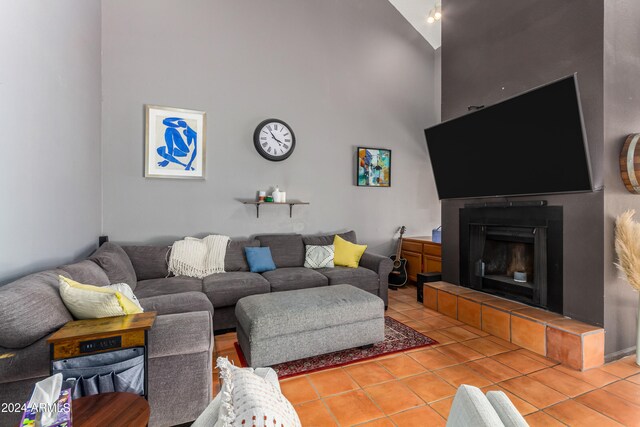 living room featuring high vaulted ceiling, tile patterned floors, and a fireplace