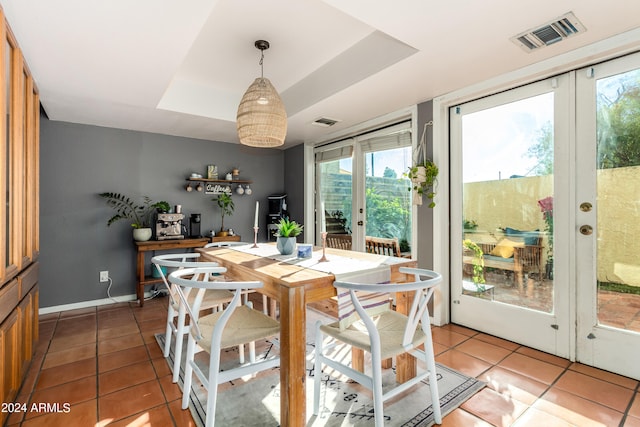 tiled dining room featuring french doors, a tray ceiling, and plenty of natural light