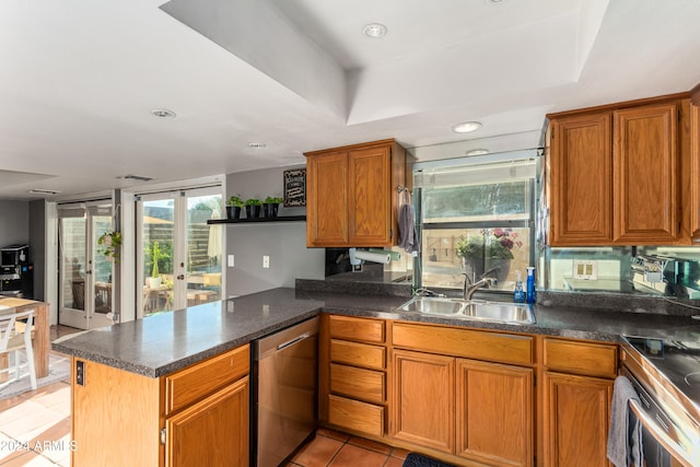 kitchen with kitchen peninsula, a tray ceiling, sink, light tile patterned floors, and appliances with stainless steel finishes