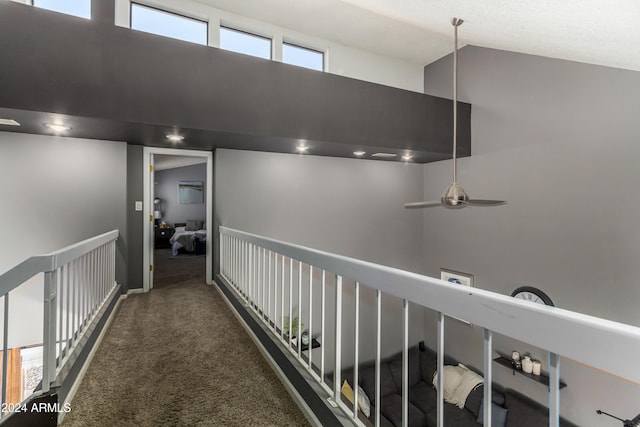 hallway featuring high vaulted ceiling and dark colored carpet