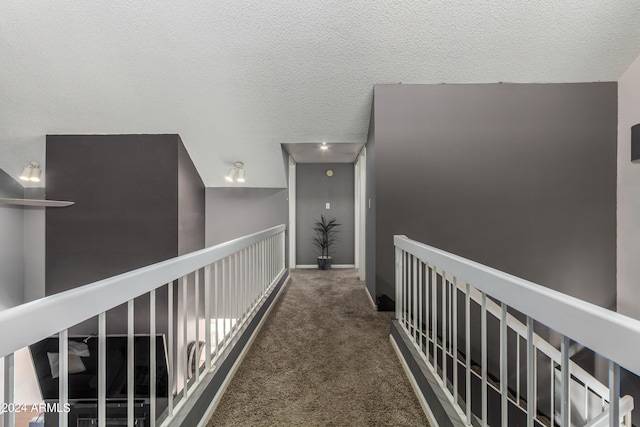 hallway featuring a textured ceiling and dark colored carpet