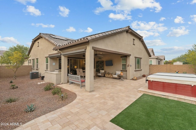 back of property with outdoor lounge area, a patio, central AC, and a hot tub