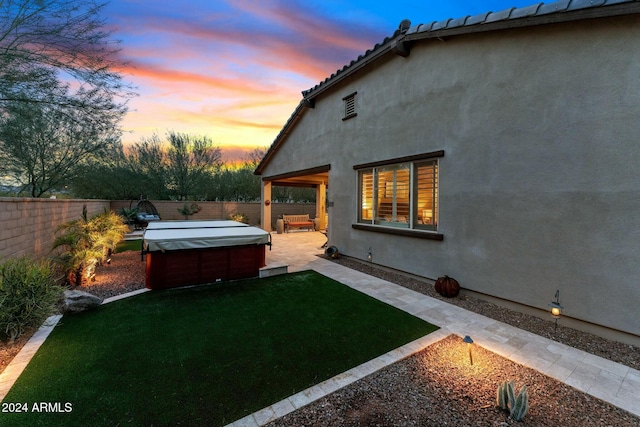 yard at dusk featuring a hot tub and a patio area