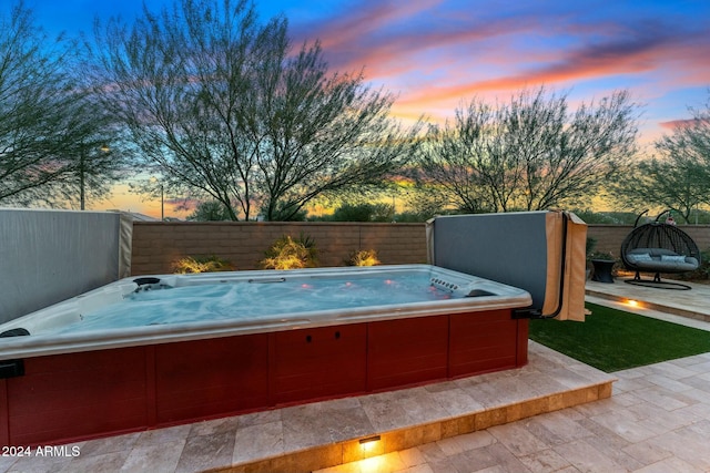 pool at dusk featuring a hot tub