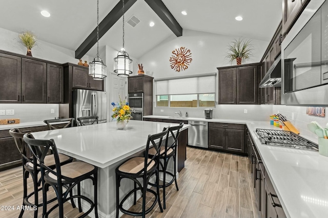 kitchen featuring tasteful backsplash, lofted ceiling with beams, hanging light fixtures, and stainless steel appliances