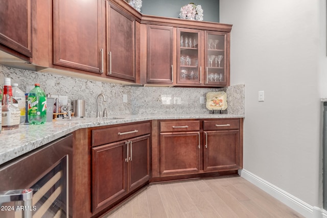 kitchen with sink, light stone counters, backsplash, and beverage cooler