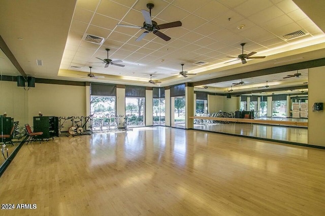 exercise room with a drop ceiling, a tray ceiling, and hardwood / wood-style flooring