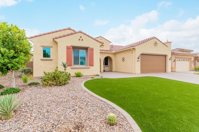 mediterranean / spanish-style home featuring a front lawn and a garage