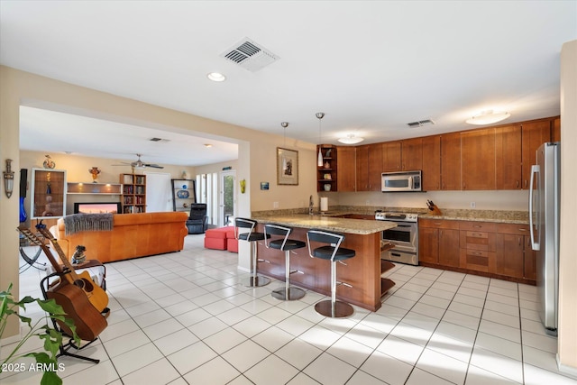 kitchen featuring open shelves, visible vents, appliances with stainless steel finishes, open floor plan, and a peninsula