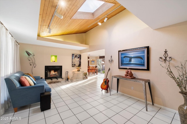 living area with wood ceiling, a skylight, a warm lit fireplace, and track lighting