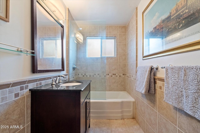 full bathroom featuring tile patterned flooring, vanity, tile walls,  shower combination, and wainscoting