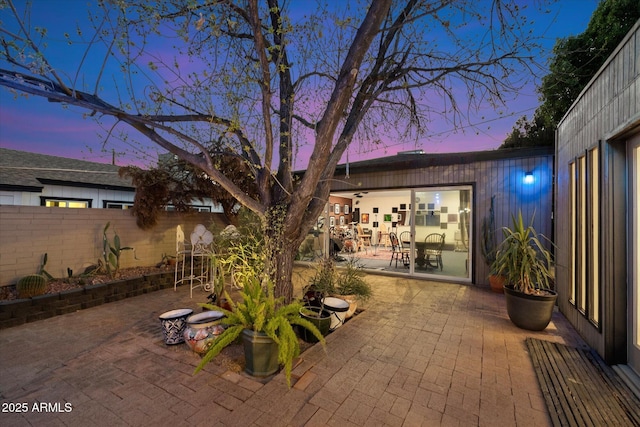 patio terrace at dusk featuring fence