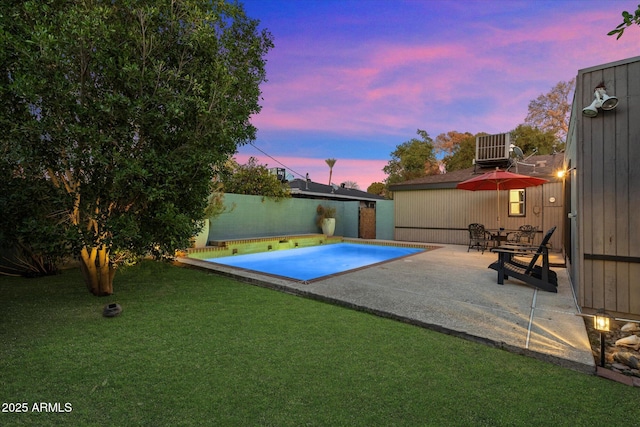 view of swimming pool with a patio, central AC, fence, a yard, and a fenced in pool