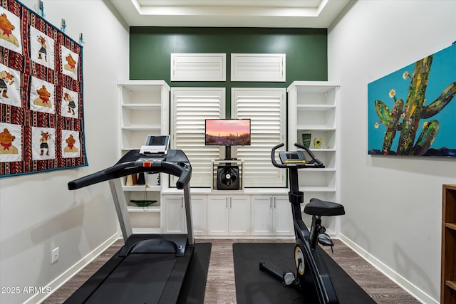 exercise area with baseboards and dark wood finished floors